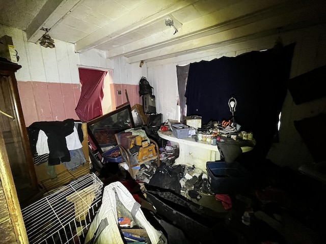 miscellaneous room with beamed ceiling and wood walls