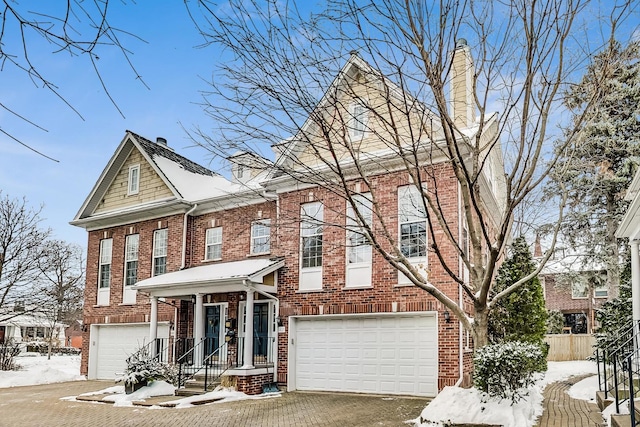 view of front of property with an attached garage, brick siding, fence, driveway, and a chimney