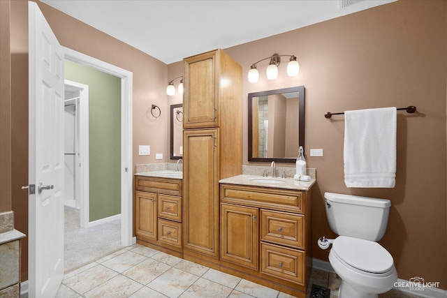 bathroom with double vanity, a sink, toilet, and tile patterned floors