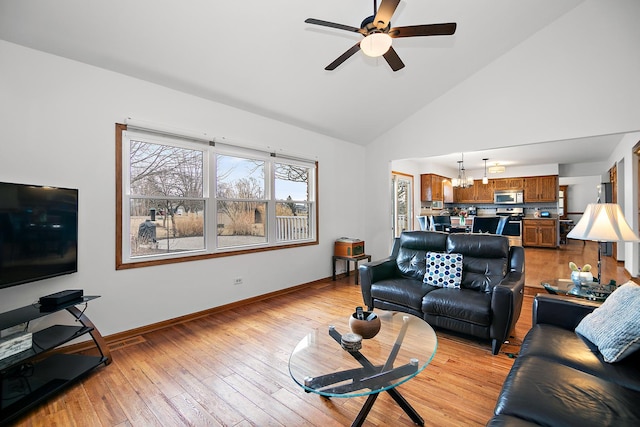 living area featuring light wood finished floors, baseboards, high vaulted ceiling, and ceiling fan with notable chandelier