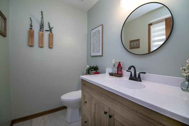 bathroom with toilet, vanity, and baseboards