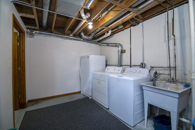 laundry area with laundry area, separate washer and dryer, a sink, and baseboards