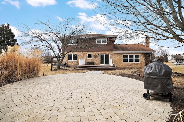 back of house with a patio area, a chimney, a deck, and brick siding