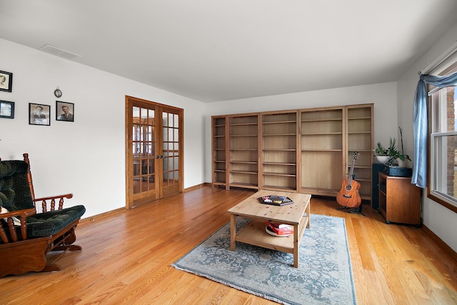 living area featuring baseboards, visible vents, wood finished floors, and french doors