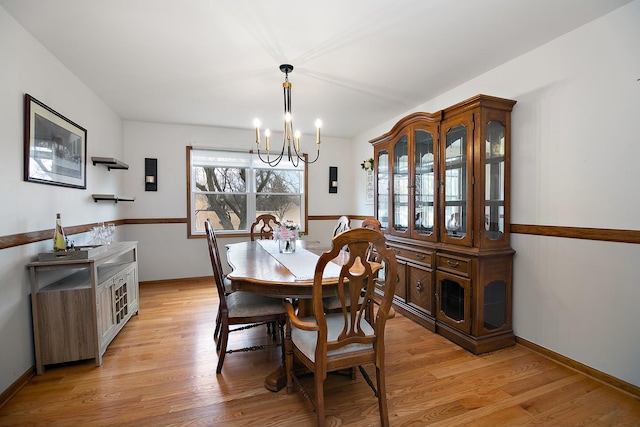 dining area with light wood-type flooring, an inviting chandelier, and baseboards