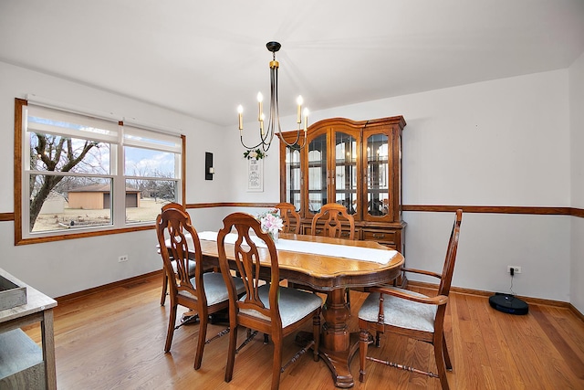 dining room featuring a chandelier, baseboards, and light wood finished floors