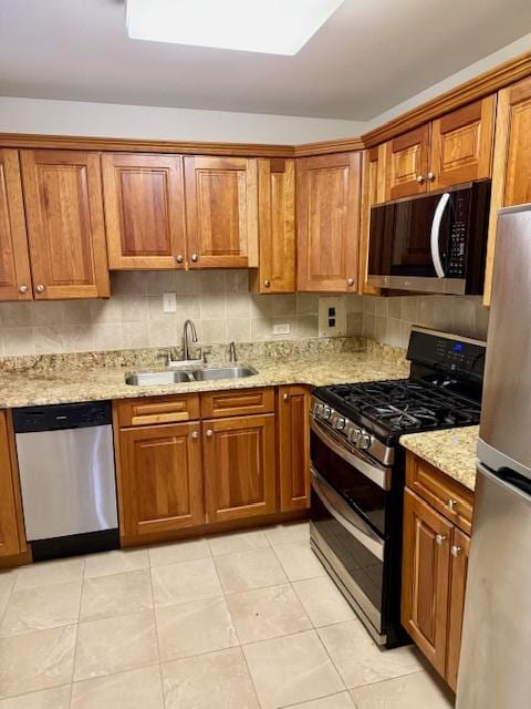 kitchen with brown cabinets, appliances with stainless steel finishes, a sink, and decorative backsplash