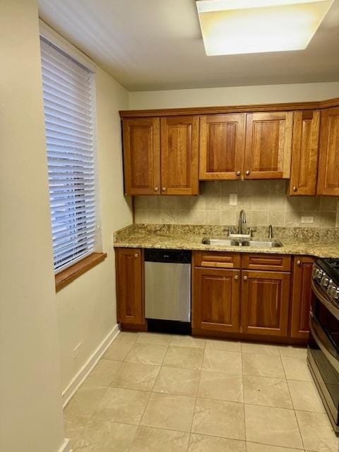 kitchen with light tile patterned flooring, a sink, appliances with stainless steel finishes, light stone countertops, and tasteful backsplash