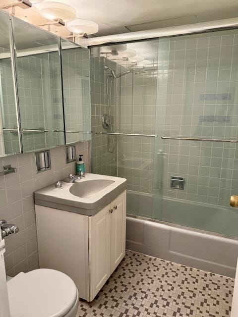 bathroom featuring shower / bath combination with glass door, tile walls, backsplash, toilet, and vanity