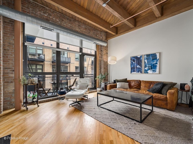 living room with wood-type flooring, brick wall, a towering ceiling, wooden ceiling, and beamed ceiling