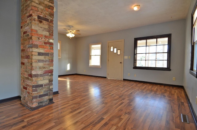 unfurnished living room featuring dark wood-type flooring and ceiling fan