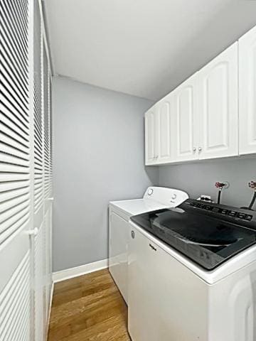 clothes washing area featuring cabinet space, baseboards, washer and clothes dryer, and wood finished floors