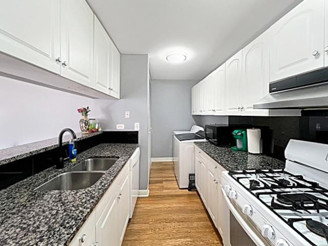 kitchen with under cabinet range hood, white appliances, a sink, white cabinets, and washer and clothes dryer