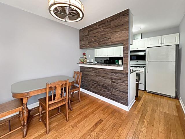 kitchen with white appliances, baseboards, light countertops, light wood-type flooring, and white cabinetry