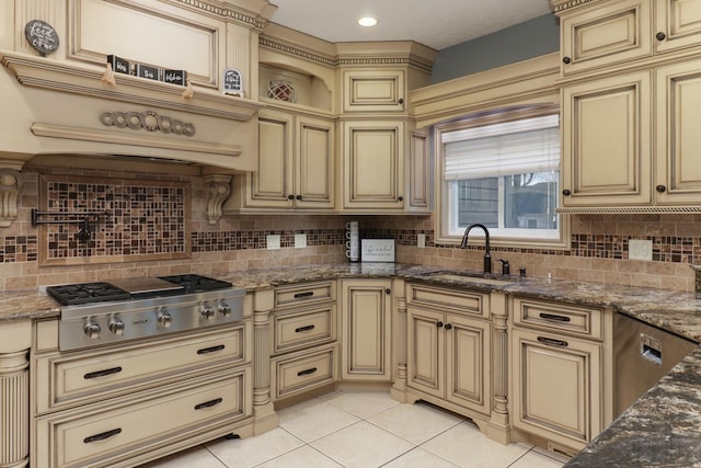 kitchen with light tile patterned floors, stainless steel gas cooktop, a sink, cream cabinetry, and backsplash