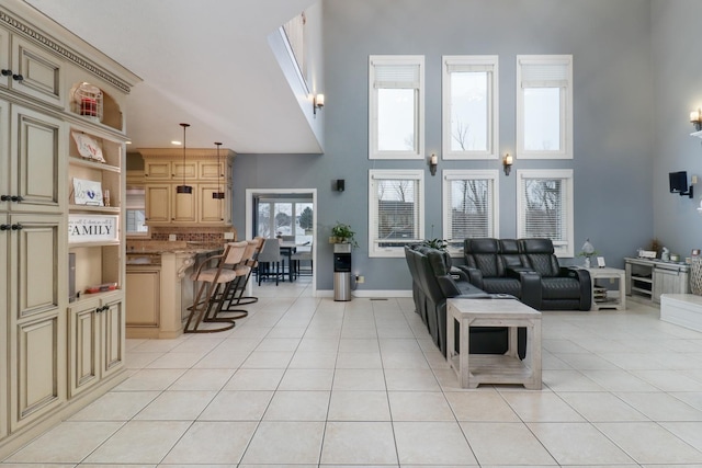 living area featuring a towering ceiling, light tile patterned floors, and baseboards