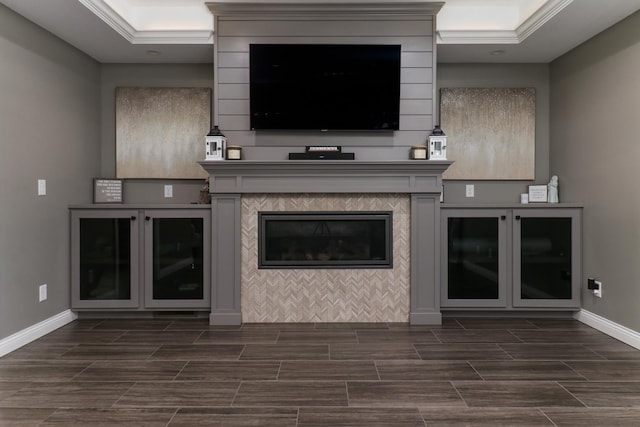 unfurnished living room with a tray ceiling, wood tiled floor, baseboards, and a tiled fireplace