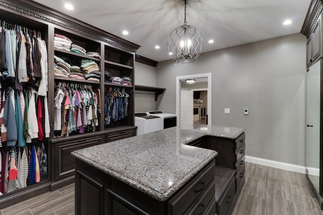 walk in closet featuring wood finish floors, a notable chandelier, and independent washer and dryer