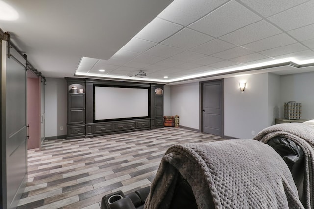 home theater room featuring a barn door, baseboards, and a drop ceiling