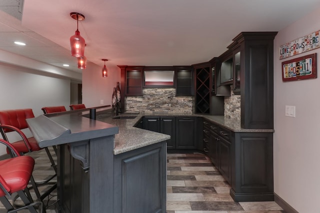 bar featuring tasteful backsplash, wet bar, a sink, and pendant lighting