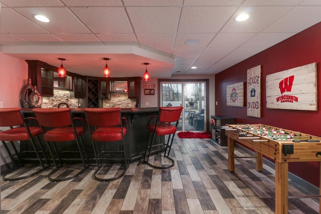 bar featuring hanging light fixtures, tasteful backsplash, indoor bar, and dark wood finished floors