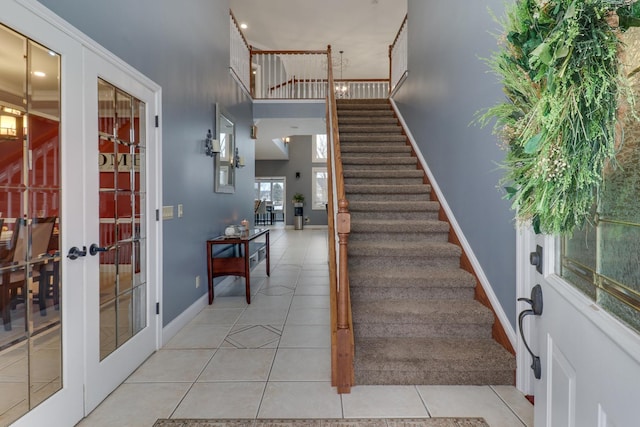 entryway with french doors, light tile patterned flooring, baseboards, and stairs