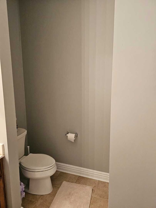 bathroom with toilet, vanity, and tile patterned flooring