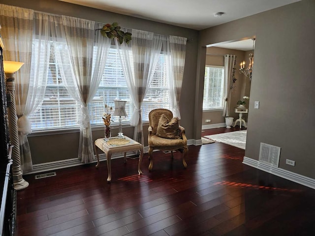 sitting room with dark wood-type flooring and an inviting chandelier