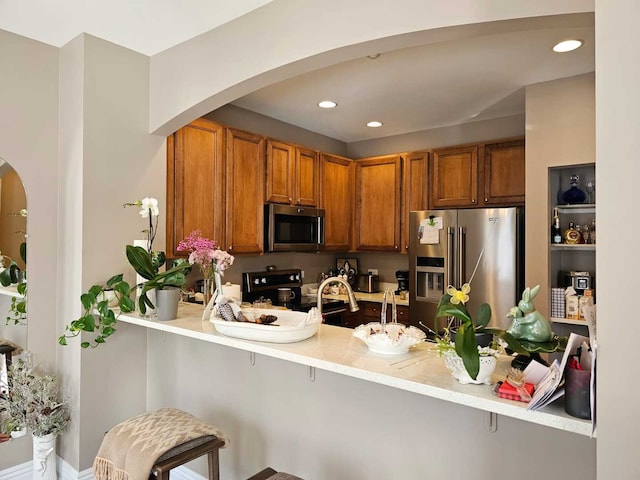 kitchen featuring appliances with stainless steel finishes, kitchen peninsula, and a breakfast bar area