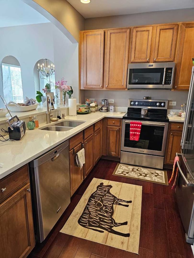 kitchen with appliances with stainless steel finishes, sink, and dark hardwood / wood-style floors