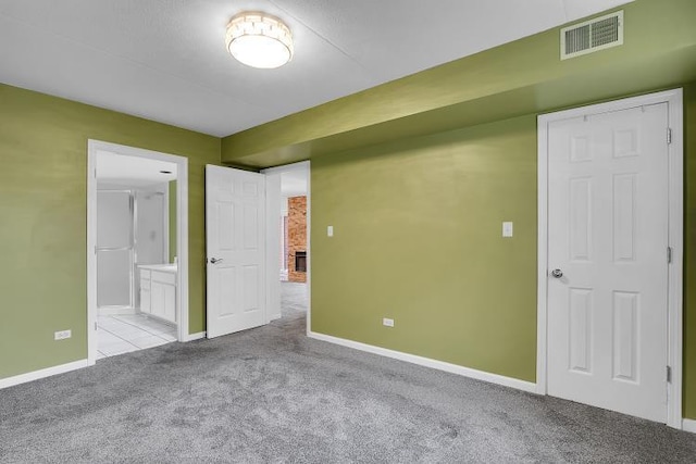 unfurnished bedroom featuring connected bathroom and light carpet