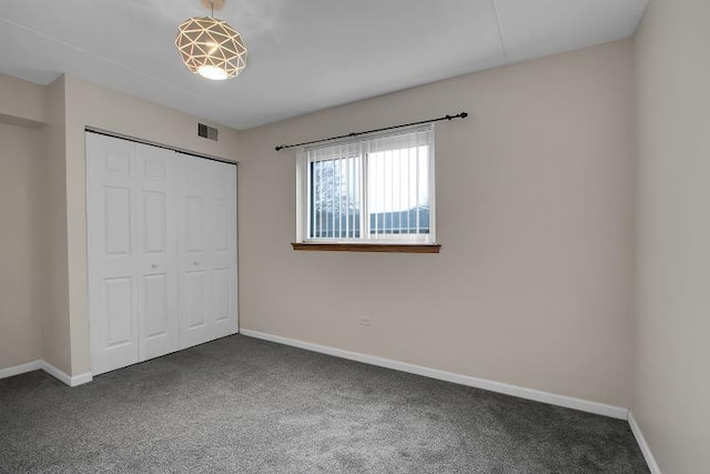 unfurnished bedroom featuring dark carpet and a closet