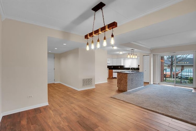 kitchen featuring ornamental molding, a notable chandelier, pendant lighting, light hardwood / wood-style floors, and white cabinets