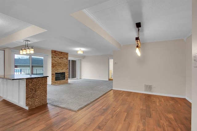 unfurnished living room featuring hardwood / wood-style floors, a stone fireplace, and ornamental molding