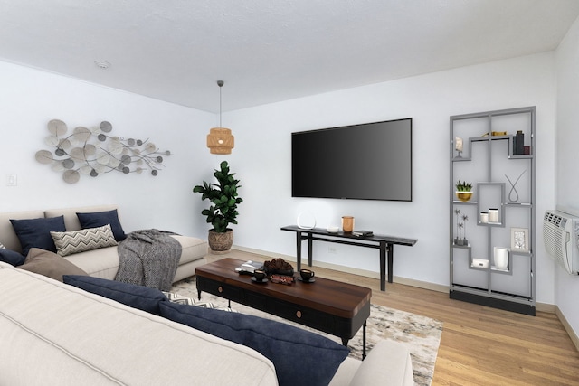 living room with a wall unit AC and light wood-type flooring