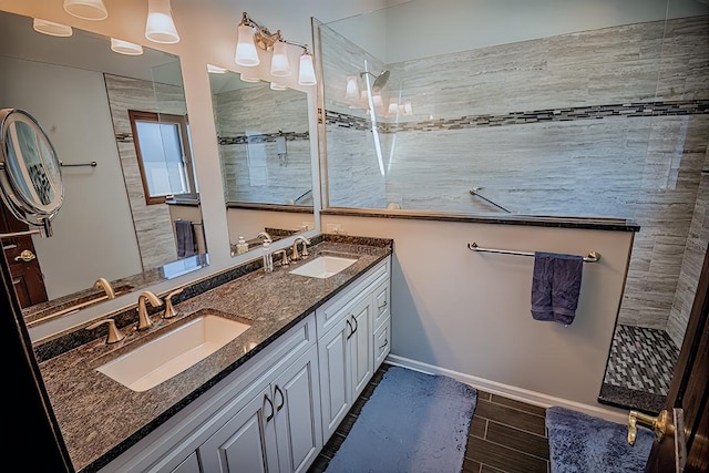 bathroom with double vanity, wood finish floors, walk in shower, and a sink