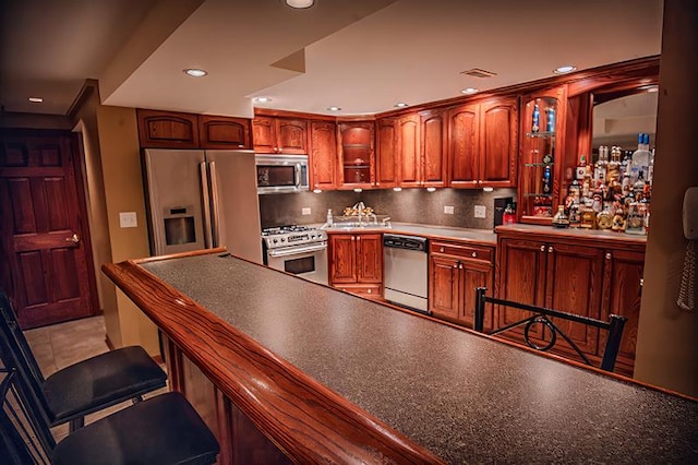 kitchen with a sink, a kitchen breakfast bar, backsplash, recessed lighting, and stainless steel appliances