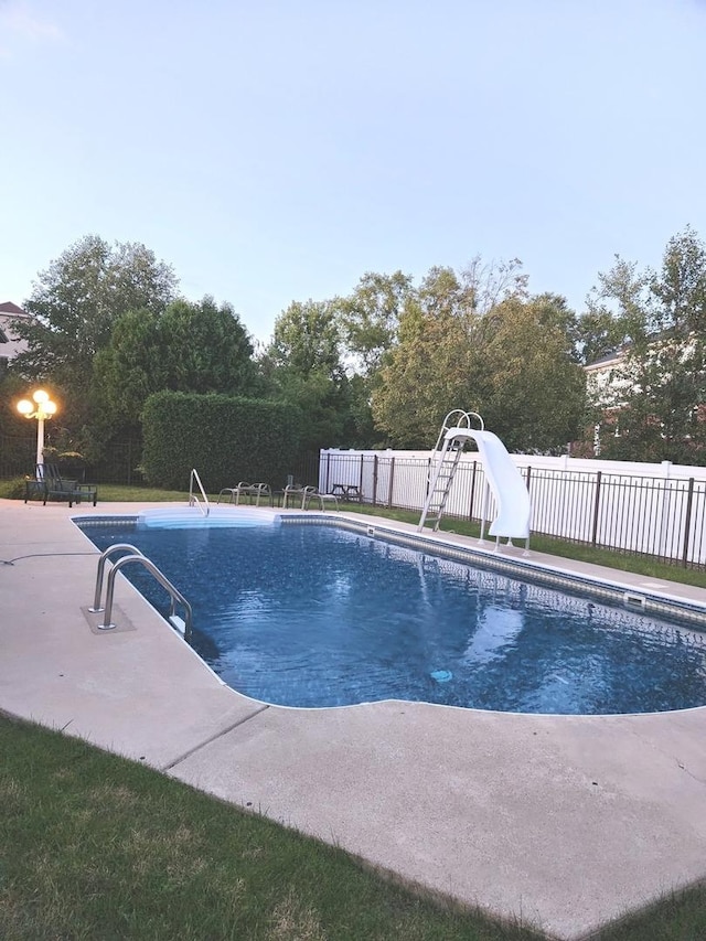 view of swimming pool featuring a fenced in pool, a water slide, a fenced backyard, and a patio area