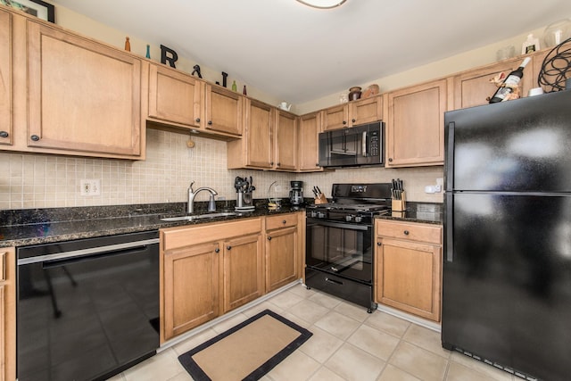 kitchen with a sink, black appliances, dark stone countertops, and tasteful backsplash