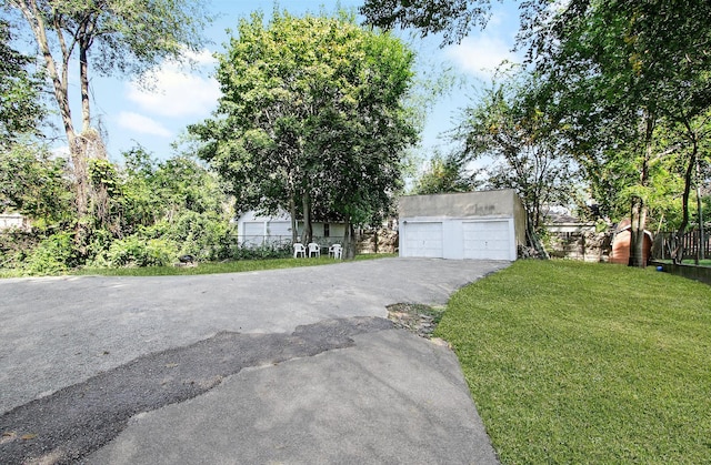 view of front of house with a front yard, a detached garage, and an outdoor structure