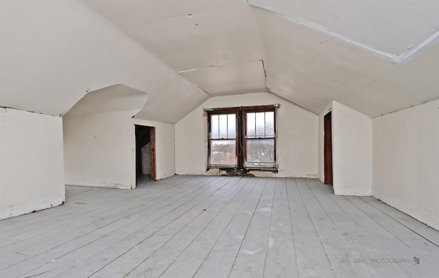 additional living space featuring light wood-type flooring and vaulted ceiling