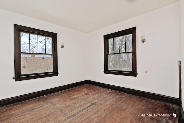 spare room featuring plenty of natural light, baseboards, and hardwood / wood-style floors