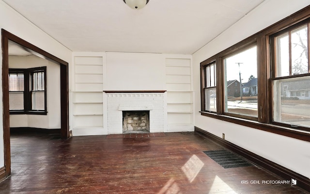 unfurnished living room featuring built in shelves, a fireplace, wood-type flooring, visible vents, and baseboards