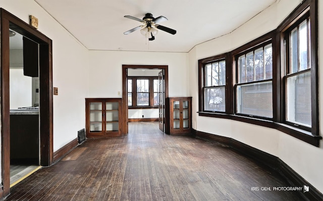 interior space with wood-type flooring, a ceiling fan, and baseboards