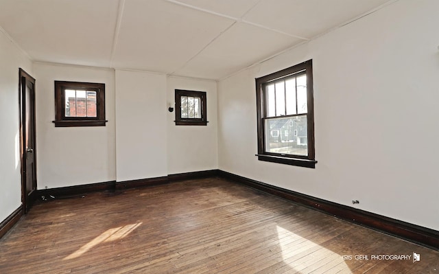 unfurnished room with baseboards, dark wood-type flooring, and a healthy amount of sunlight