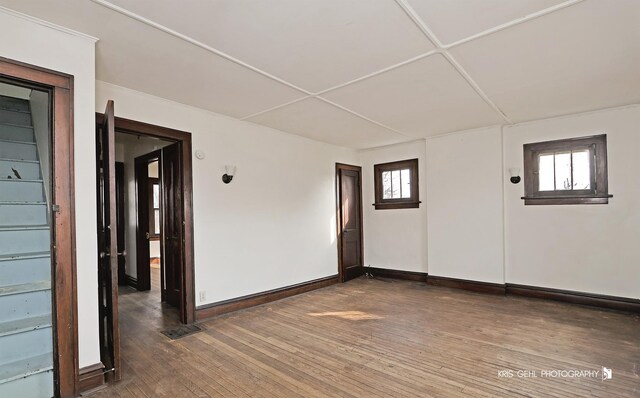 unfurnished room featuring hardwood / wood-style floors, visible vents, and baseboards