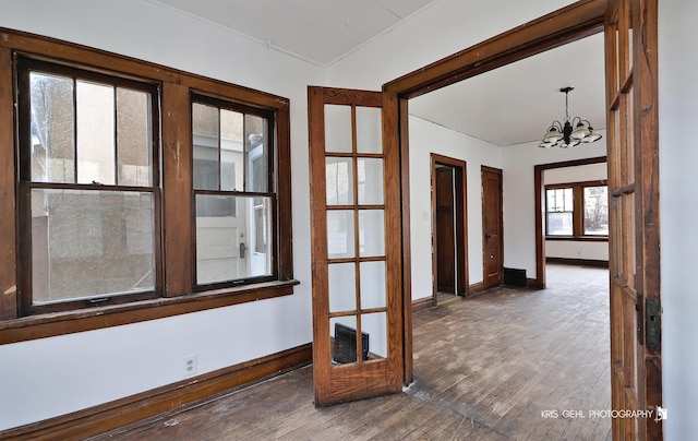 unfurnished room with hardwood / wood-style flooring, visible vents, baseboards, and a notable chandelier