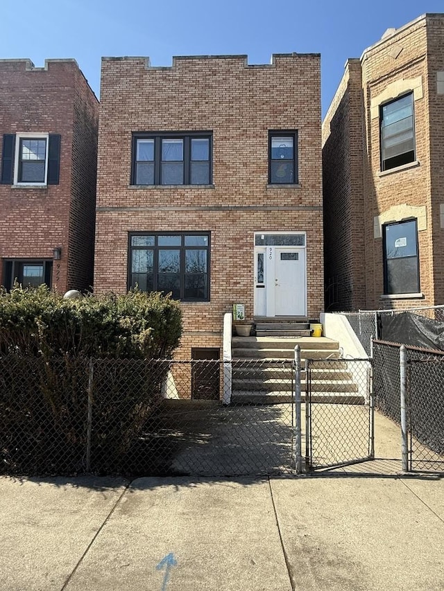 view of front of property featuring entry steps, brick siding, a fenced front yard, and a gate