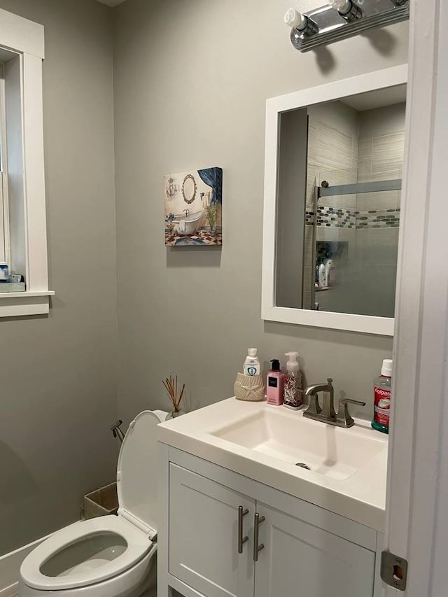 bathroom with tiled shower, vanity, and toilet