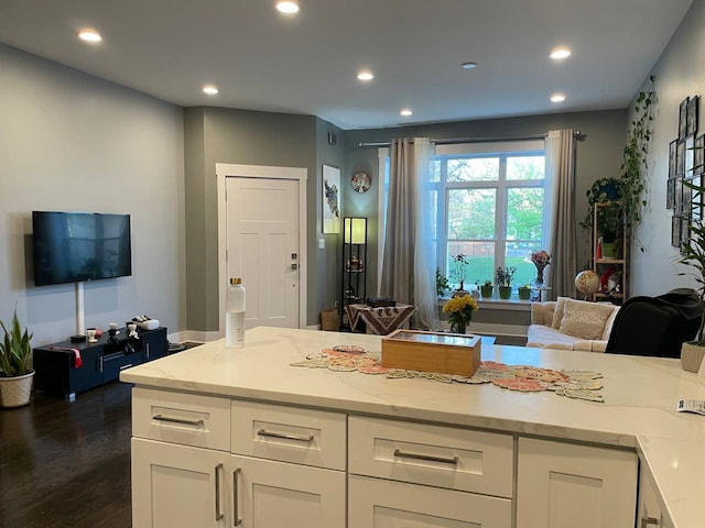 kitchen with dark wood-style floors, light stone counters, open floor plan, white cabinetry, and recessed lighting